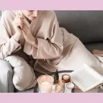 Simple Joy - woman sitting in robe at home reading a book with candles. Very cozy