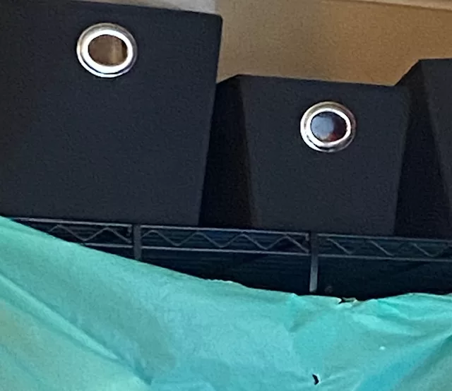 Fabric baskets holding office supplies on a rack above my greenscreen