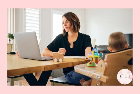 Woman working from home in front of computer with child in high chair - work life balance