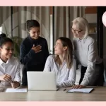 How to thank coworkers - a group of colleagues smiling at each other around a laptop