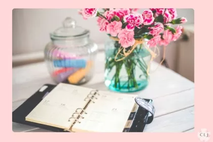 Desk planner, roses, and jar with colored chalk on an office desk at home
